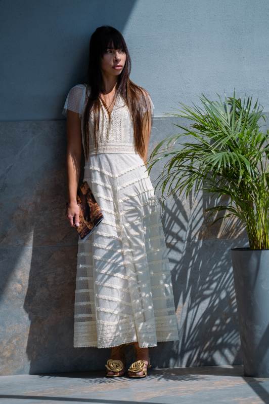 image000004 Romantyczna sukienka maxi w stylu boho-chic, stworzona z myślą o kobietach ceniących subtelną elegancję i lekkość formy. Model zachwyca efektownymi, koronkowymi falbankami z makramy oraz delikatnymi wstawkami o ażurowym wykończeniu, które nadają całości wyjątkowego charakteru. Sukienka posiada niepodszyte rękawy, które podkreślają jej zwiewność, oraz głęboki dekolt w kształcie litery V, pięknie eksponujący sylwetkę. Gorset i spódnica zdobione są misternymi detalami inspirowanymi szydełkowaniem, a całość dopełniają szerokie, poziome falbany, dodające objętości i romantycznego uroku. Model zapinany z tyłu na guzik (zapięcie typu „łezka”). Długość do kostek oraz klasyczny, regularny krój sprawiają, że sukienka doskonale dopasowuje się do sylwetki, zapewniając komfort i swobodę noszenia. Idealna na letnie przyjęcia, wakacyjne spacery czy wyjątkowe okazje.