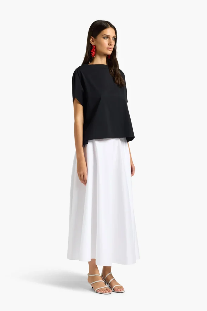 S6LL6SW64Y69 0 A Minimalistyczna bluzka o nowoczesnym, swobodnym fasonie, wykonana z lekkiej tkaniny pięknie układającej się na sylwetce. Model z szerokim, łódkowym dekoltem oraz krótkimi, luźno opadającymi rękawami podkreśla elegancki i ponadczasowy charakter projektu. Prosta forma i delikatnie oversize’owy krój sprawiają, że bluzka doskonale komponuje się zarówno z eleganckimi spódnicami, jak i casualowymi spodniami. Uniwersalny model idealny do tworzenia nowoczesnych, minimalistycznych stylizacji na co dzień i na wyjątkowe okazje.