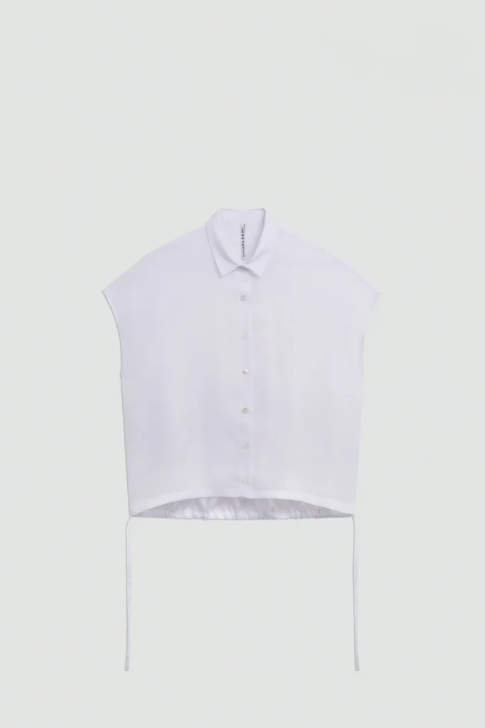 S6LL6SL05A01 0 A CAMICIA LINO MANICHE ALETTA Koszula lniana damska z rękawami typu skrzydełka to idealne połączenie komfortu, naturalnych materiałów i ponadczasowego stylu. Wykonana w 100% z wysokiej jakości lnu, zapewnia doskonałą przewiewność i wygodę noszenia nawet podczas najcieplejszych dni. Naturalny len jest ceniony za swoje właściwości oddychające, trwałość oraz lekkość, dzięki czemu koszula świetnie sprawdzi się w sezonie wiosenno-letnim. Model wyróżnia się subtelnymi rękawami typu skrzydełka, które nadają sylwetce lekkości i kobiecego charakteru. Centralne zapięcie z kontrastującymi, widocznymi guzikami stanowi modny detal podkreślający wyjątkowy design koszuli. Dodatkowym atutem są boczne sznurki umieszczone przy dolnym wykończeniu, które pozwalają na regulację długości oraz indywidualne dopasowanie fasonu do sylwetki i stylizacji. Ta letnia koszula damska doskonale komponuje się zarówno ze spodniami lnianymi, jeansami, jak i spódnicami. Sprawdzi się podczas codziennych wyjść, wakacyjnych podróży oraz w eleganckich, casualowych stylizacjach. Jeśli szukasz uniwersalnej koszuli z lnu, która łączy naturalny komfort z modnym wyglądem, ten model będzie doskonałym wyborem do każdej garderoby.