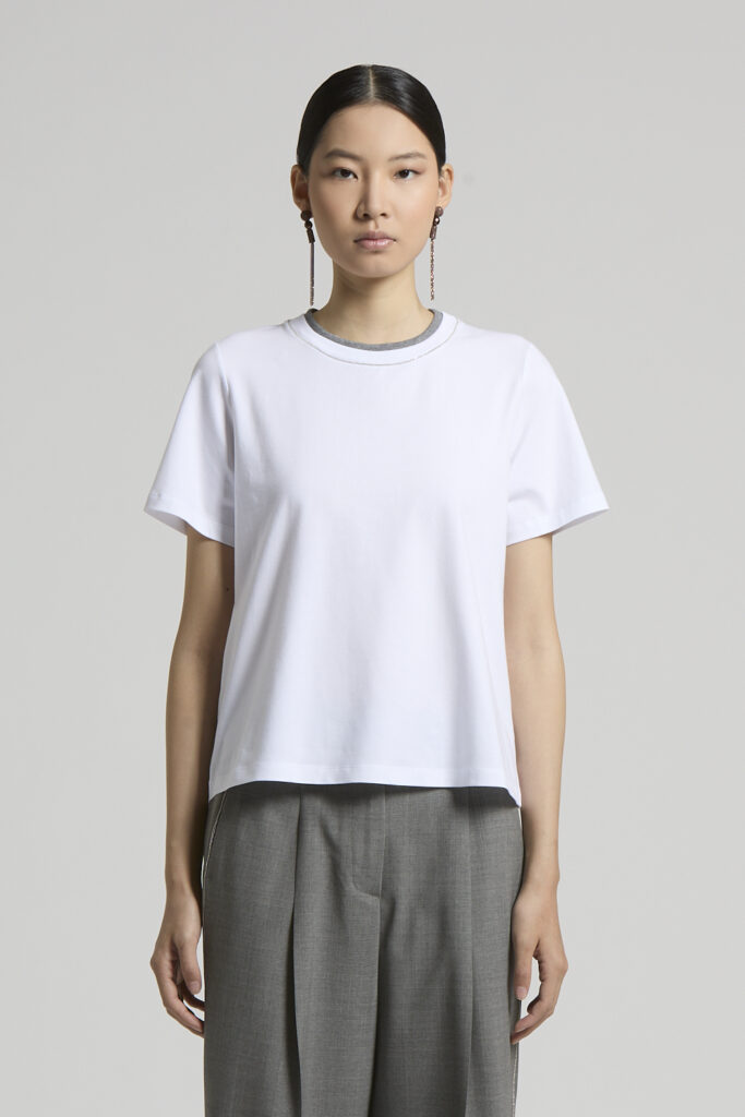 A06864J0 00079 001 T-shirt damski Peserico to ponadczasowa baza garderoby, która łączy minimalistyczny design z najwyższą jakością wykonania. Wykonany z miękkiej, wysokogatunkowej bawełny premium, zapewnia wyjątkowy komfort noszenia, doskonałą przewiewność i idealnie układa się na sylwetce. Model posiada klasyczny okrągły dekolt z subtelnym kontrastowym wykończeniem oraz krótkie rękawy, dzięki czemu doskonale sprawdzi się zarówno w codziennych, jak i eleganckich stylizacjach. Prosty, lekko swobodny fason sprawia, że koszulka świetnie komponuje się z jeansami, spodniami garniturowymi, spódnicami czy marynarką, tworząc stylowy zestaw na każdą okazję. Charakterystyczna dla marki Peserico dbałość o detale i precyzja wykonania sprawiają, że ten model to doskonały wybór dla kobiet ceniących luksusową modę w nowoczesnym wydaniu.