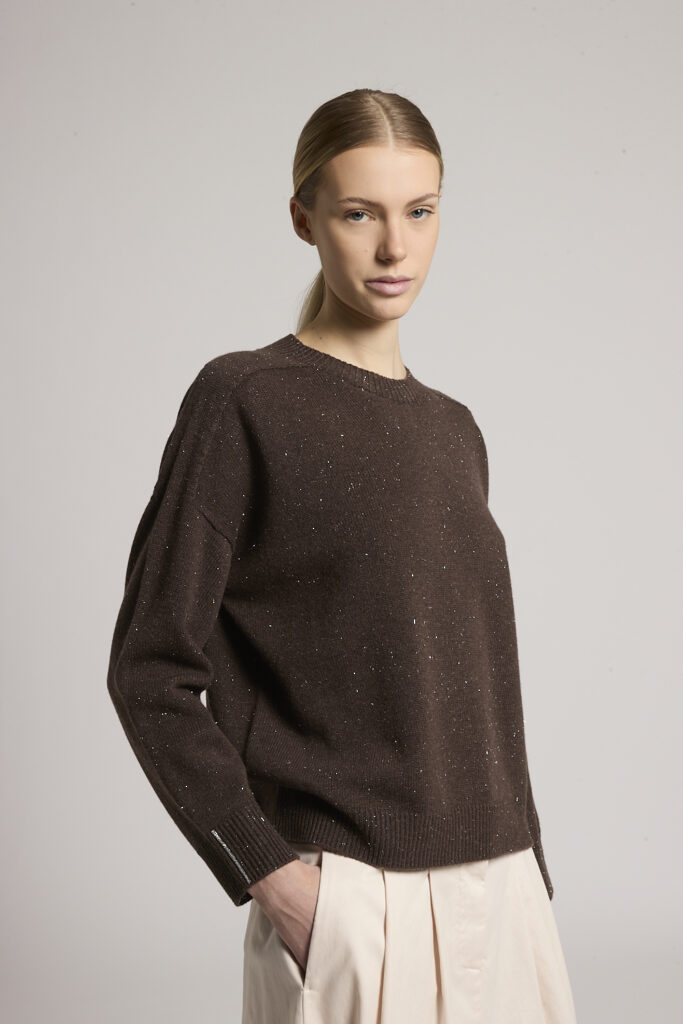 S99984F07K 09095 252 4 Elegancki sweter Peserico wykonany z luksusowej mieszanki wełny, jedwabiu i kaszmiru, która zapewnia wyjątkową miękkość, lekkość oraz komfort noszenia. Model zachwyca prostym, ponadczasowym fasonem z okrągłym dekoltem i swobodnie opadającymi ramionami, dzięki czemu doskonale układa się na sylwetce. Czekoladowy odcień został subtelnie wzbogacony delikatnym połyskującym efektem, który dodaje całości elegancji i charakterystycznego dla marki Peserico wyrafinowanego stylu. Ściągacze przy dekolcie, mankietach i dole podkreślają klasyczny wygląd, a ozdobny detal Punto Luce przy mankietach stanowi eleganckie wykończenie. To uniwersalny model, który doskonale komponuje się zarówno z eleganckimi spodniami i spódnicami, jak i z jeansami, tworząc stylowe zestawy na każdą okazję.