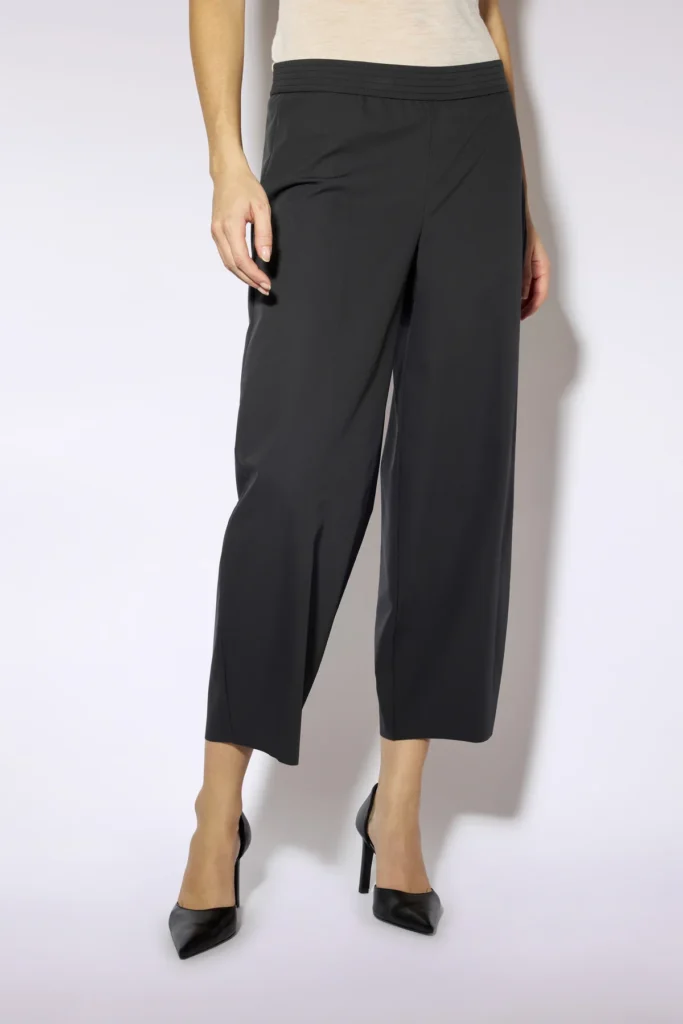W6FF6WR62Y49 0 B PANTALONE HARPER 60aae77d e39a 4c10 aad9 04c45acdd342 Spodnie barrel Liviana Conti to propozycja dla kobiet, które cenią minimalistyczny styl, wygodę i ponadczasowy design. Charakterystyczny fason barrel leg z lekko zaokrągloną nogawką nadaje sylwetce nowoczesnego charakteru, zachowując jednocześnie elegancki wygląd. Model został wykonany z lekkiej, elastycznej tkaniny, która zapewnia komfort noszenia przez cały dzień. Elastyczny pas gwarantuje idealne dopasowanie do sylwetki, a długość 7/8 sprawia, że spodnie doskonale prezentują się zarówno z klasycznymi szpilkami, mokasynami, jak i sneakersami. Minimalistyczne wykończenie i brak zbędnych detali podkreślają wyrafinowany styl charakterystyczny dla włoskiej marki Liviana Conti. Czarne spodnie barrel to uniwersalny element garderoby, który z łatwością dopasujesz do koszuli, dzianinowego swetra, marynarki czy prostego T-shirtu, tworząc stylizacje odpowiednie zarówno do pracy, jak i na co dzień.