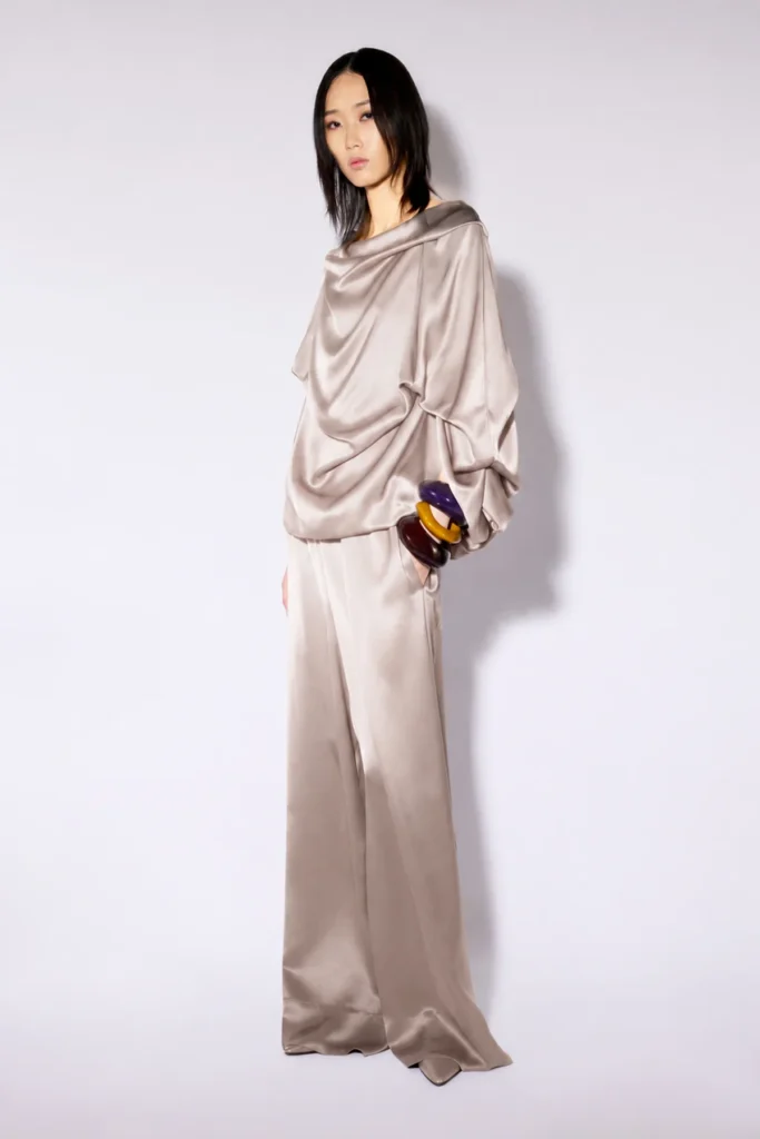 W6FF6WS84X36 0 A 1 Satynowe spodnie maxi Liviana Conti to model z tej samej kapsułowej kolekcji co satynowa kurtka bomber, tworzące z nią&nbsp; harmonijny i niezwykle elegancki total look. Wykonane z delikatnie połyskującej tkaniny, zachwycają minimalistycznym designem oraz komfortowym, swobodnym krojem. Szerokie nogawki o długości maxi pięknie układają się podczas ruchu, nadając sylwetce lekkości i wyrafinowanego charakteru. Elastyczna talia ze sznurkiem do regulacji zapewnia idealne dopasowanie oraz wygodę noszenia przez cały dzień. Subtelny satynowy połysk podkreśla luksusowy charakter modelu, dzięki czemu spodnie doskonale sprawdzą się zarówno na wyjątkowe okazje, jak i w codziennych stylizacjach. Połącz je z satynową bomberką Liviana Conti z tej samej kolekcji, aby stworzyć spójny, nowoczesny komplet inspirowany włoskim stylem.